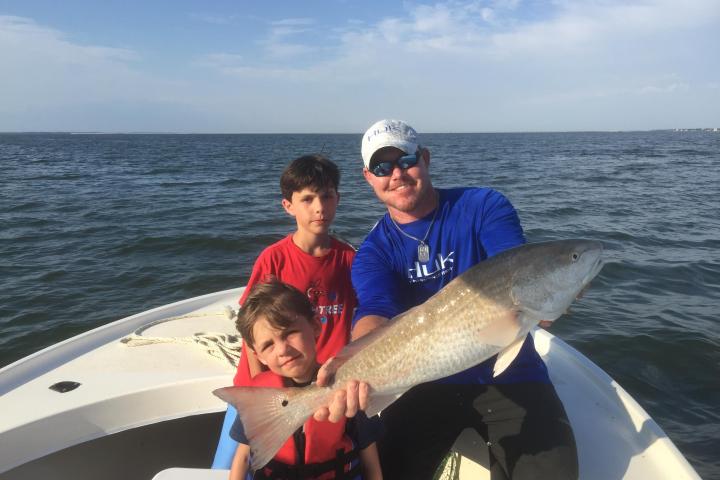 a man holding a fish on a boat in a body of water