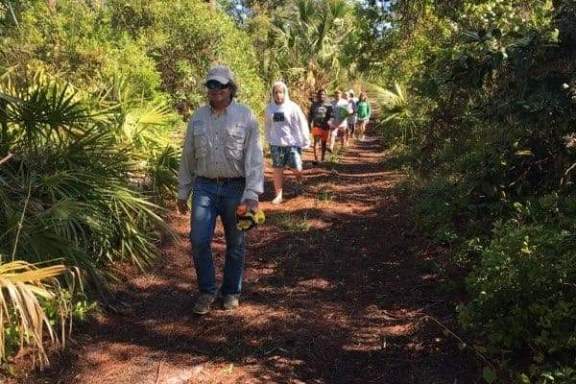 a group of people on a dirt path next to a tree
