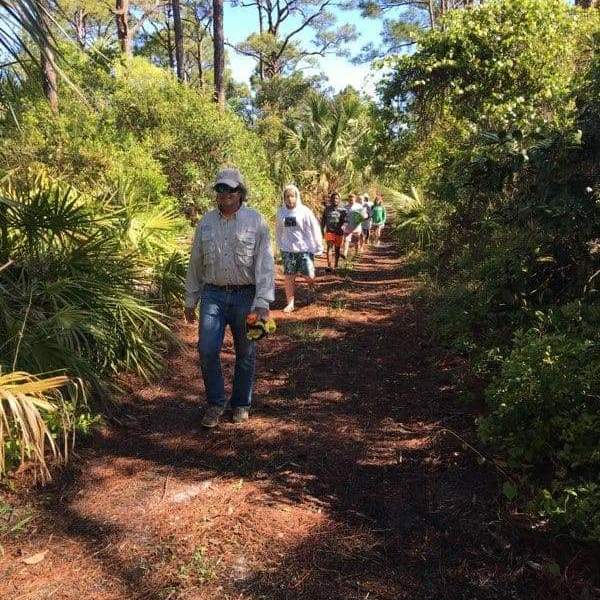 a group of people on a dirt path next to a tree